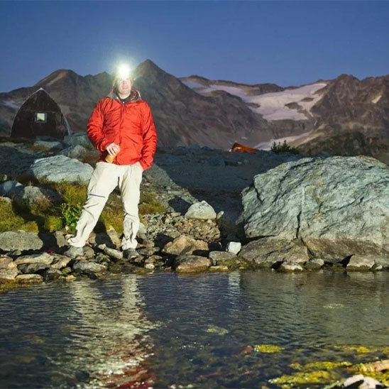 homme eclaire riviere avec frontale lampe