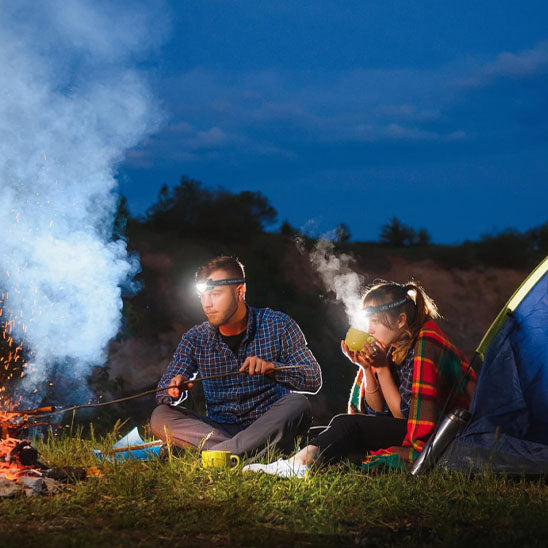 homme femme assis camping avec frontale lampe 
