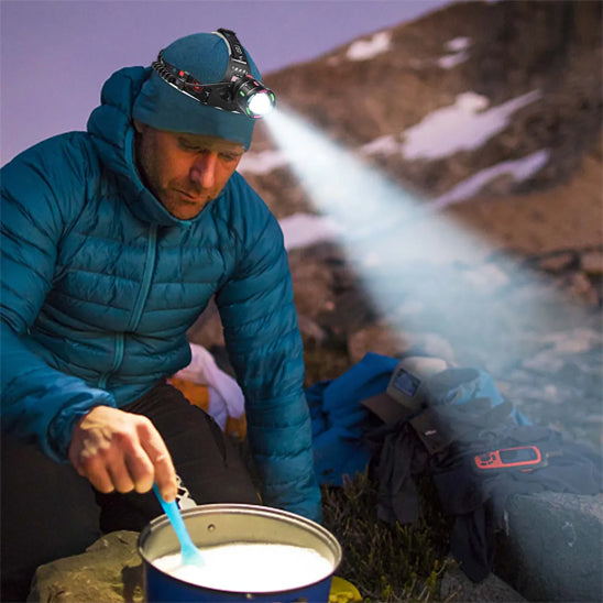 homme montagne cuisinant avec lampe frontale puissante