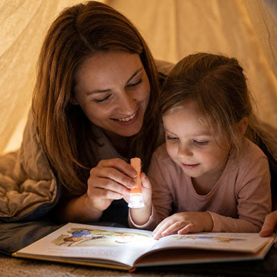 petite fille regarde livre avec lampe torche enfant avec maman